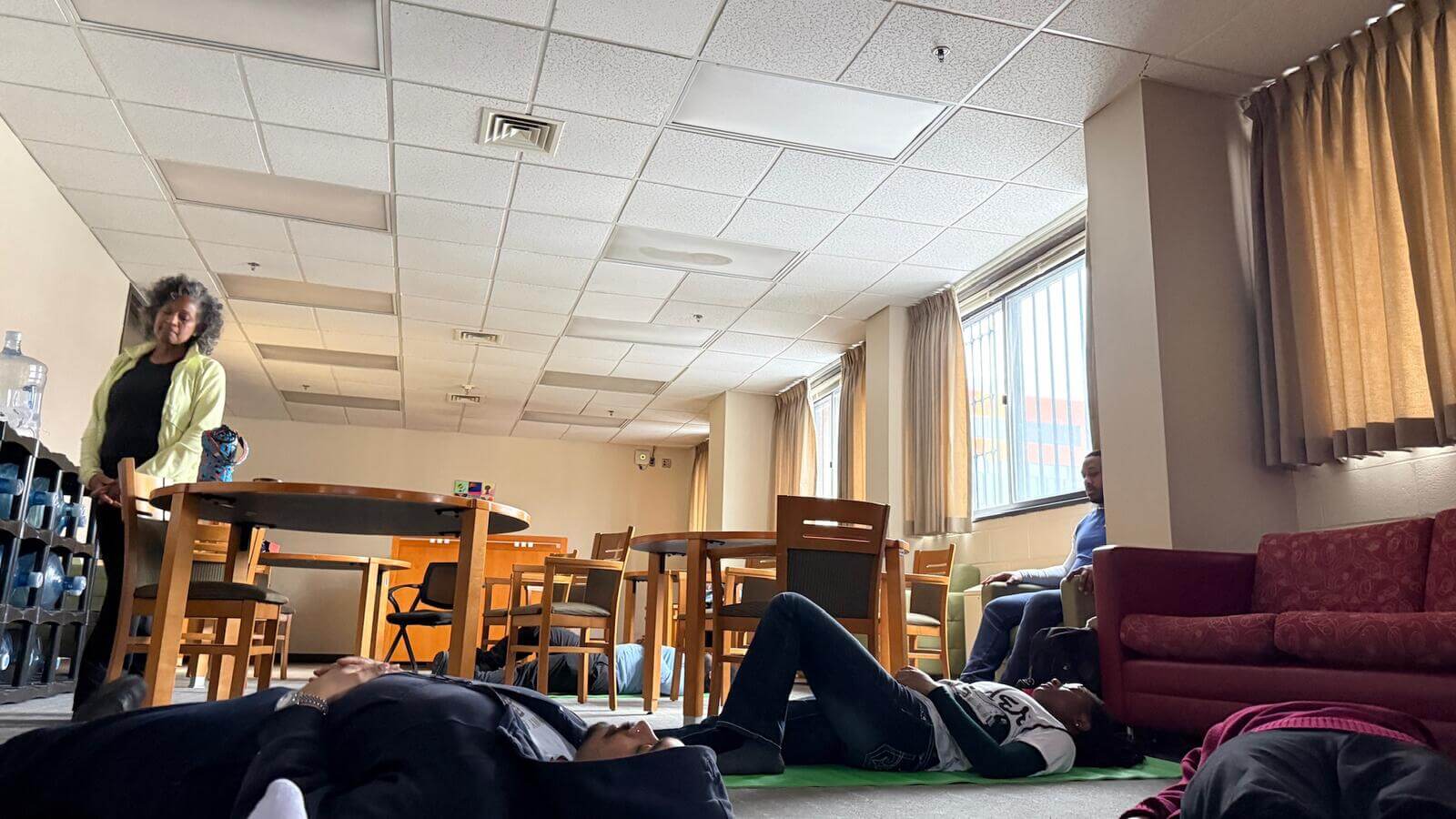 Meditation class from a participant's perspective lying down and looking at the instructor